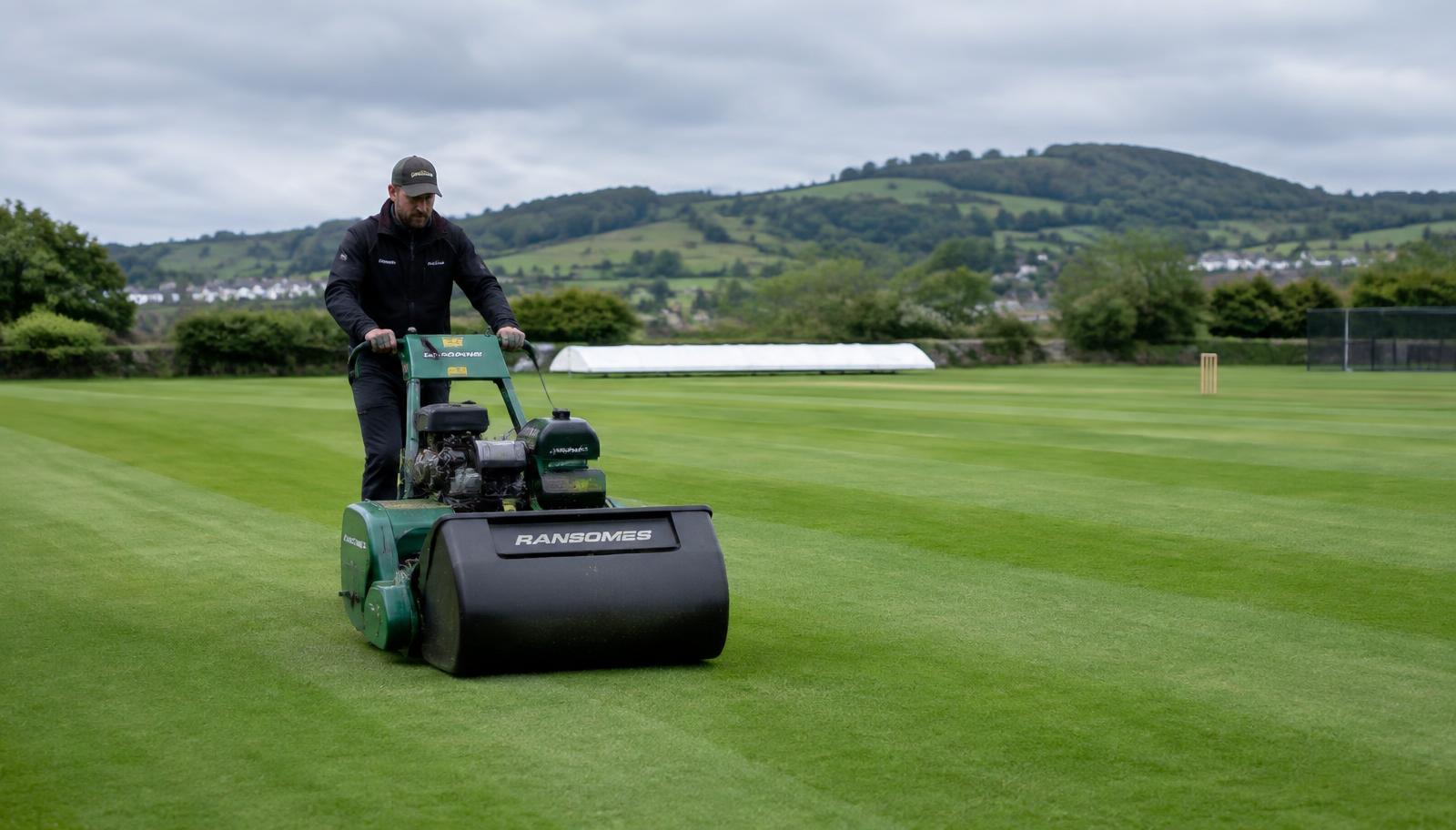 Groundsman mowing a Devon cricket outfield